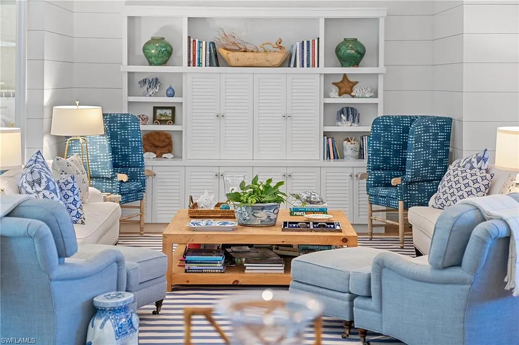 Blue upholstered chairs and white sofas around a wooden coffee table in a bright living room